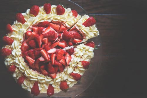 a cake with strawberries on a glass plate on a table at The Ship Inn in Mousehole