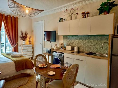 Il comprend une petite cuisine avec une table et une chambre. dans l'établissement Studio 23m2 Le Grand Hotel en hyper centre-ville avec balcon, à Aix-les-Bains
