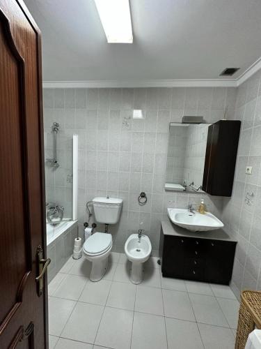a white bathroom with a toilet and a sink at Apartamento da praia in Ovar