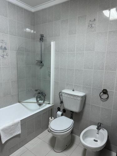 a bathroom with a toilet and a tub and a sink at Apartamento da praia in Ovar