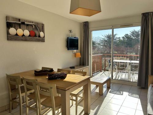 un salon avec une table et des chaises et un balcon dans l'établissement 100 - Appart duplex 6p avec piscine collective., à Fréhel