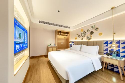 a bedroom with a large white bed and a tv at O LIVE Social Hotel Guangzhou Station Baima Clothing City in Guangzhou