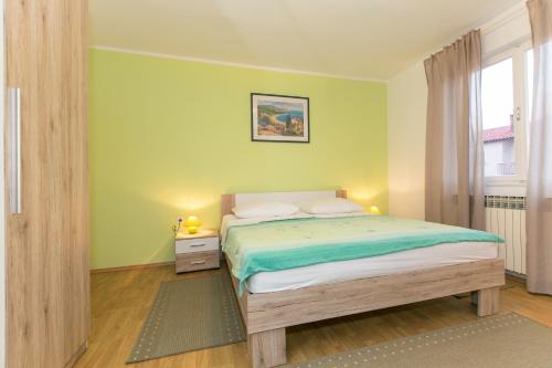 - une chambre avec un lit aux murs verts et une fenêtre dans l'établissement Apartment Amalia, à Labin