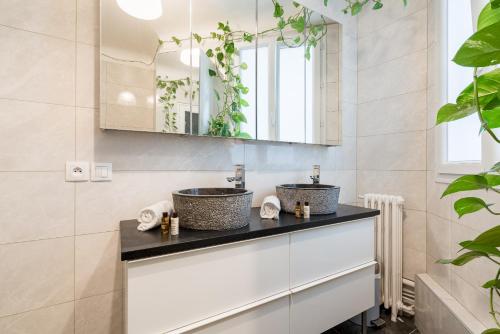 deux lavabos dans une salle de bain avec un miroir et des plantes dans l'établissement Veeve - The Seaferer, à Paris