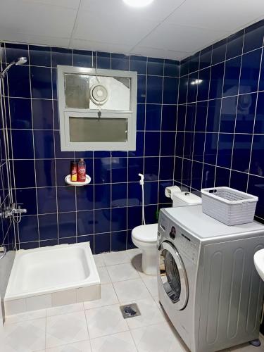 a blue tiled bathroom with a washing machine in it at Ajman Friends Downtown Apartment Fully Yours Two Rooms and Kitchen for 3 People in Ajman 