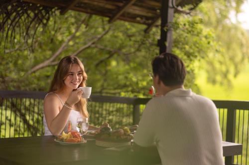 a man and woman sitting at a table with a cup of coffee at SigiriyaJungles Resort & Spa in Sigiriya