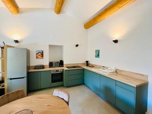 a kitchen with green cabinets and a wooden table at La tanière d'Agoult in Goult