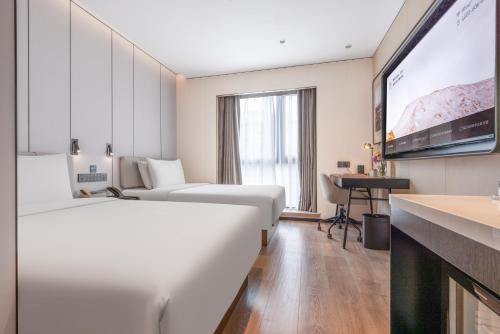 a hotel room with two beds and a flat screen tv at Atour Hotel Beijing Sanlitun North Gongti Road in Beijing