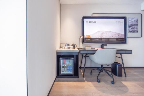 a computer monitor sitting on a desk with a chair at Atour Hotel Beijing Sanlitun North Gongti Road in Beijing