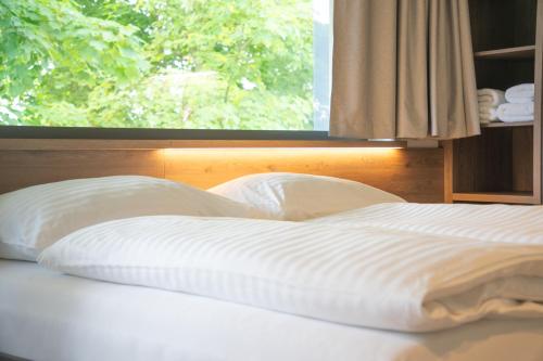 a bed with two pillows in front of a window at Penzion Lesni in Milovice