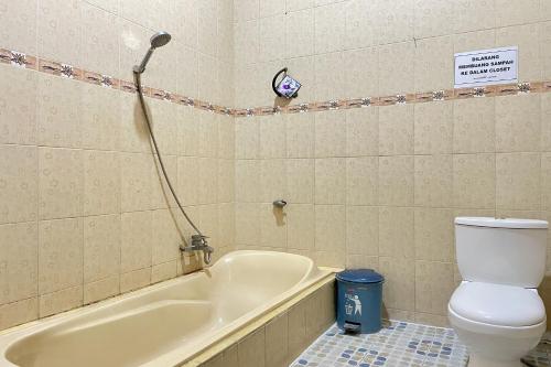 a bathroom with a toilet and a tub with a shower at Hotel Ramayana Garut in Garut