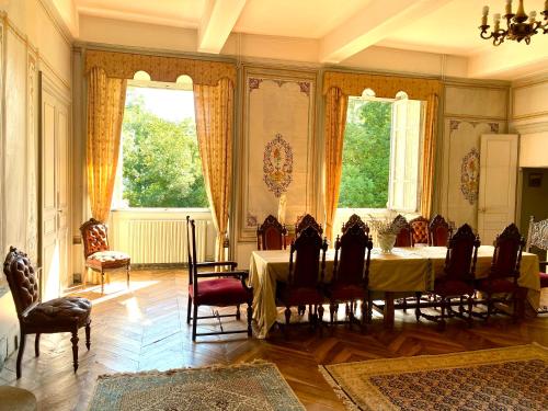 une salle à manger avec une table et des chaises et deux fenêtres dans l'établissement Château de Blot, à Blot-lʼÉglise
