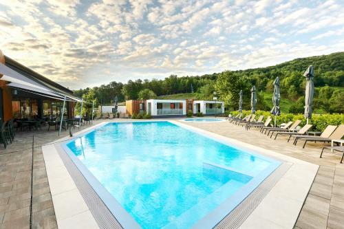 ein großer Swimmingpool mit Liegen und Sonnenschirmen in der Unterkunft Mobile Homes Camping Plitvice in Smoljanac