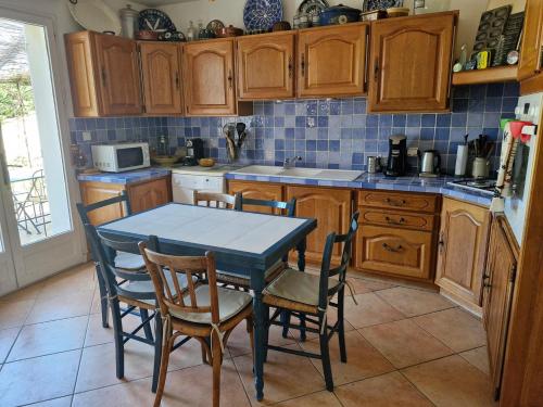 une cuisine avec des armoires en bois et une table et des chaises dans l'établissement Villa avec jacuzzi au cœur de la Provence !, à Monteux
