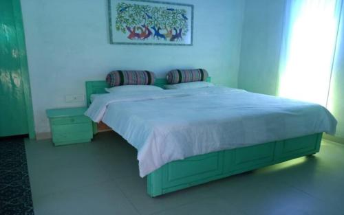 a green bed in a bedroom with a blue wall at Tiger Safari Lodge in Dodi