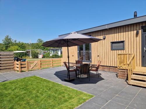 a patio with a table and chairs under an umbrella at Camping Alkenhaer Appelscha Chalet 017 in Appelscha