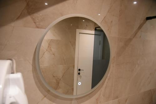 a bathroom with a round mirror and a door at L&L Apartman in Smederevska Palanka