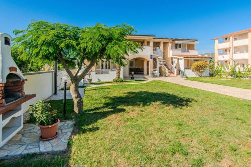 a house with a tree in front of a yard at Apartments with parking spaces Zukve, Zadar - 24559 in Nin