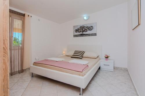 a white bedroom with a bed and a window at Apartments with parking spaces Zukve, Zadar - 24559 in Nin