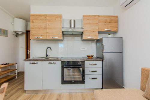 a kitchen with white cabinets and a stainless steel refrigerator at Apartments with parking spaces Zukve, Zadar - 24559 in Nin