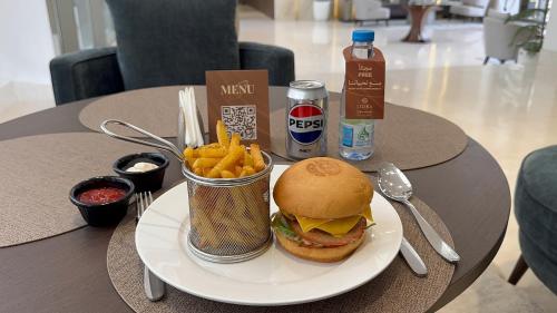 a plate with a hamburger and french fries on a table at Liora ليورا in Riyadh