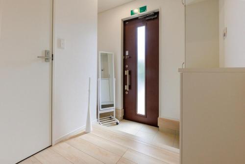 a hallway with a brown door and a mirror at 那覇空港から15分DMM水族館とイーアス豊崎近く最大10名oKの南部リゾート宿OKS inn in Itoman