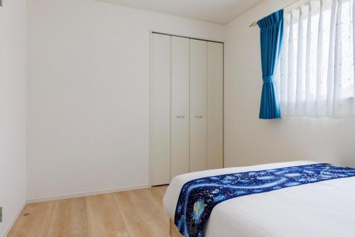 a bedroom with a bed and a blue curtain at 那覇空港から15分DMM水族館とイーアス豊崎近く最大10名oKの南部リゾート宿OKS inn in Itoman