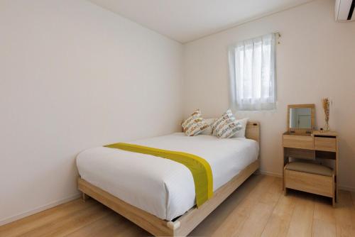 a white bedroom with a bed and a window at 那覇空港から15分DMM水族館とイーアス豊崎近く最大10名oKの南部リゾート宿OKS inn in Itoman