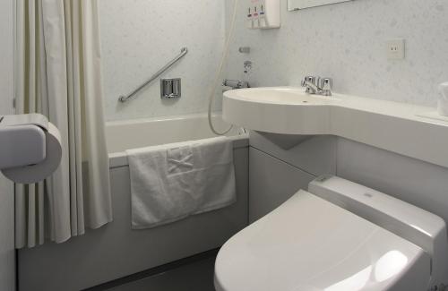 uma casa de banho com um WC branco e um lavatório. em Hotel Flex em Hiroshima
