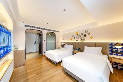 a hotel room with two beds and a tv at O LIVE Social Hotel Guangzhou Station Baima Clothing City in Guangzhou
