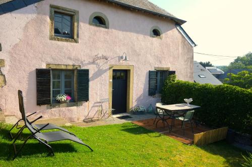 a house with a table and chairs in the yard at Au Petit Bercail - Le Fonteny - Gîte 2 personnes in Chiny