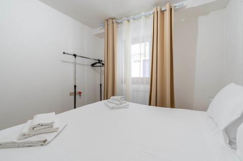 a white bed with two towels on top of it at Bricola Biennale Apartments in Venice