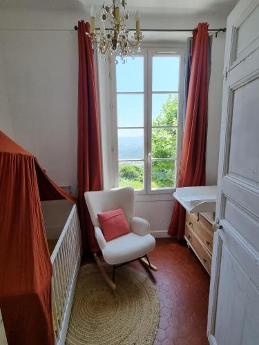 une chambre de bébé avec une chaise et une fenêtre dans l'établissement Manor house with pool, à Le Tignet