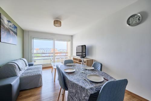 une salle à manger avec une table et des chaises et une télévision dans l'établissement Les Hirondelles - 800 m de la plage, à Courseulles-sur-Mer