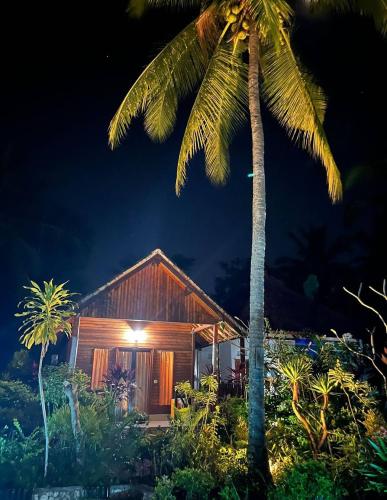 a wooden house with a palm tree in front of it at Dangin Kubu in Toyapakeh