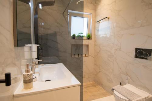 a white bathroom with a sink and a shower at Zoi Elegant Green Apartments in Filiatra