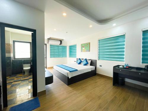 a bedroom with a bed and a bathroom with blue blinds at Xanh Melody Resort in Bắc Ninh
