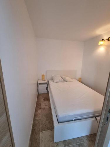 Cette petite chambre blanche comprend un lit. dans l'établissement Le Sunrise - Appartement à deux pas de la plage, à Narbonne