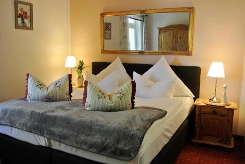 a bedroom with a bed with white pillows and a mirror at Seehotel Lindenhof in Lychen