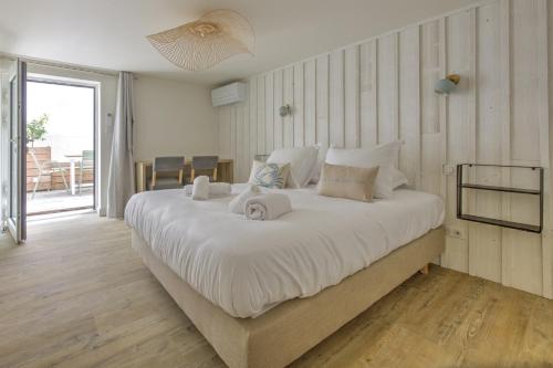une chambre avec un grand lit avec des draps blancs dans l'établissement L'instant Bassin - Proche plage dArcachon, à Arcachon