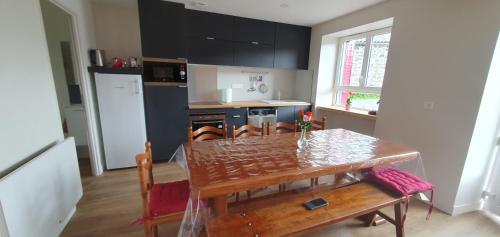 une cuisine avec une table en bois et une table et des chaises dans l'établissement Gîte Le Côme 7 -10 personnes, à Saint-Ours