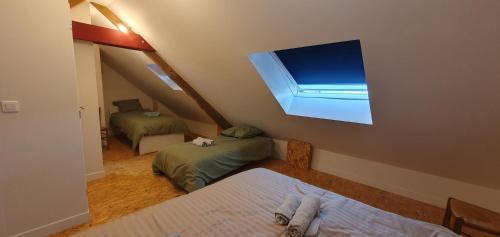 Cette chambre mansardée comprend 2 lits et une fenêtre. dans l'établissement Gîte Le Côme 7 -10 personnes, à Saint-Ours
