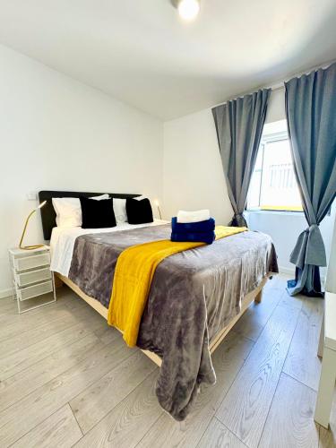 a bedroom with a large bed with a yellow blanket at BrightHouse Nazaré - Modern Apartments in Nazaré