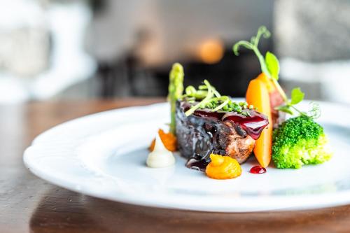 a white plate of food with broccoli and carrots at Hotel Bodega EL GRIFO in San Bartolomé