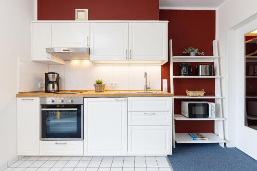 a white kitchen with white cabinets and appliances at Haus Panorama Laboe Nr 1 in Laboe