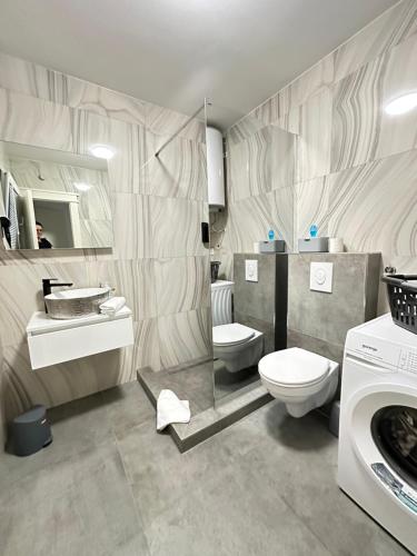 a bathroom with a toilet and a sink and a washing machine at La Familia in Šibenik
