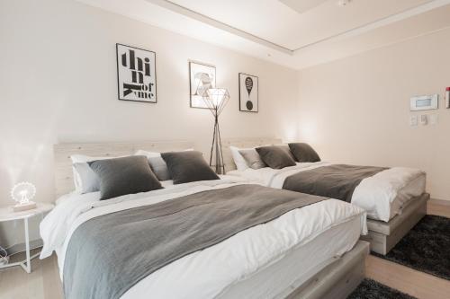 deux lits dans une chambre aux murs blancs dans l'établissement Seoul Station Sky Lounge House, à Séoul