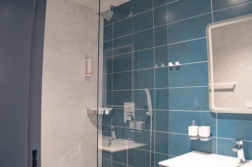 a blue tiled bathroom with a sink and a mirror at Penzion Lesni in Milovice