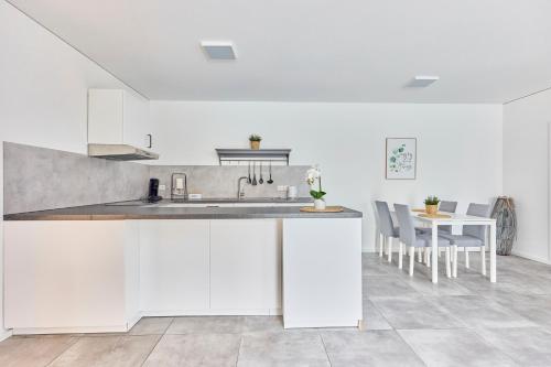 a white kitchen with a sink and a table at Zentrale Lage Netflix Queensize Bett in Bruchsal