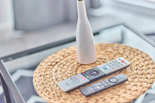 a wicker table with a vase and two remote controls at Zentrale Lage Netflix Queensize Bett in Bruchsal